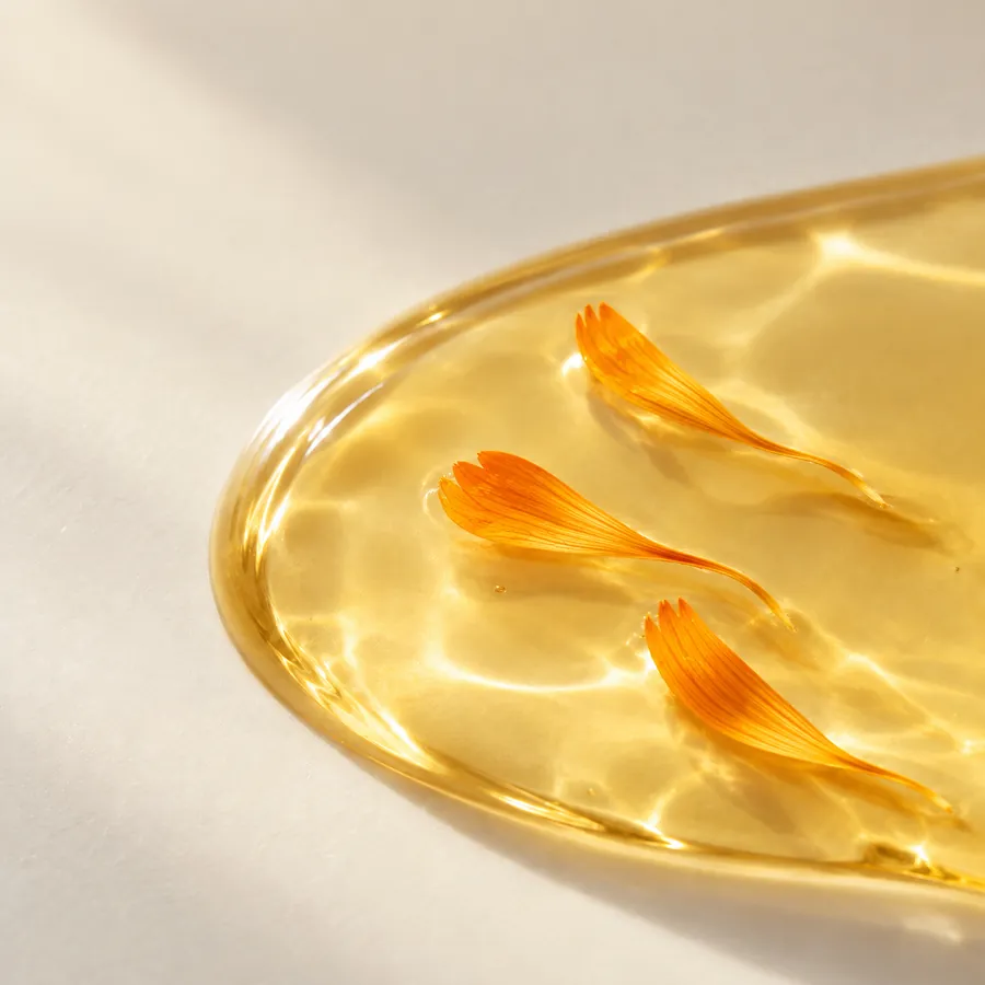 Orange calendula petals resting in a pool of golden oil